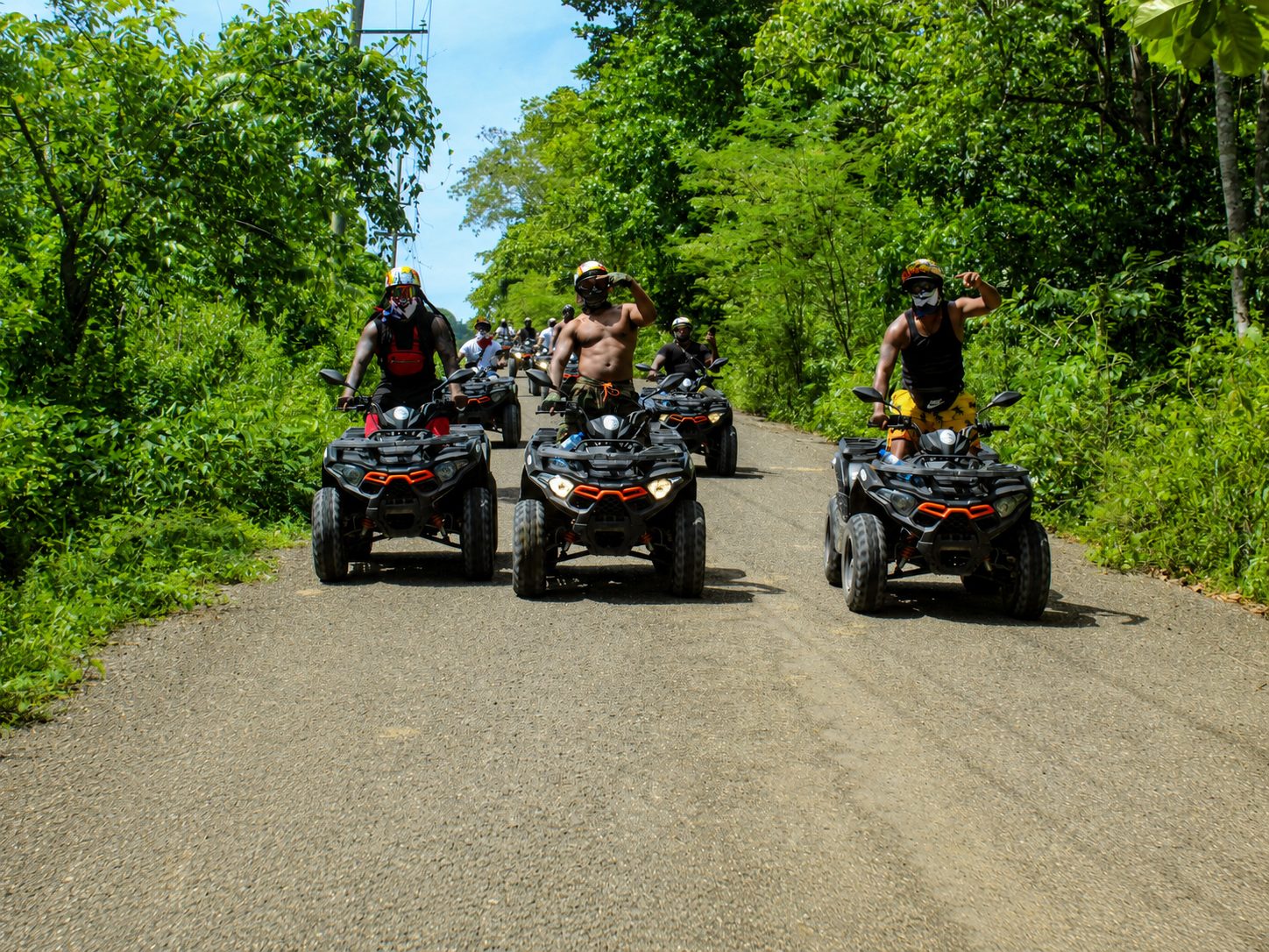 ATV riders heading down a tree-lined country road on a BlueCasas ATV tour in the Dominican Republic
