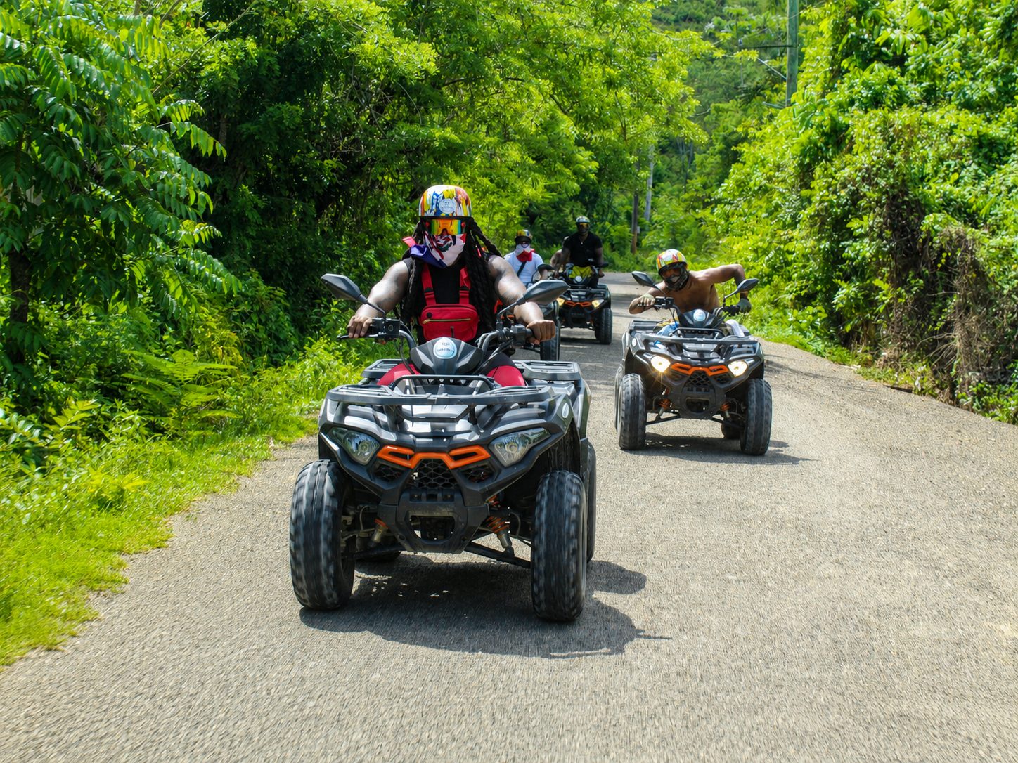 Guests riding quads on a jungle road surrounded by tropical greenery on a BlueCasas ATV tour